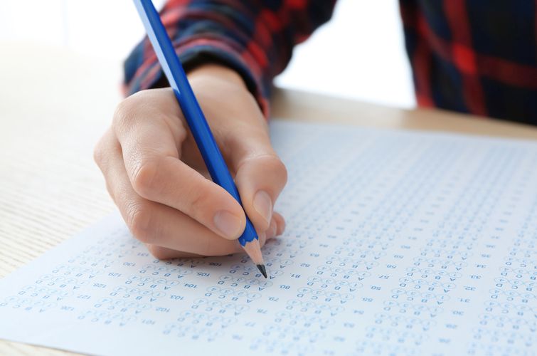 Student choosing answers in test form to pass exam at table